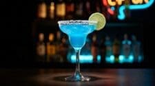 Blue Margarita in a salt-rimmed margarita glass, electric blue colour with lime wheel garnish