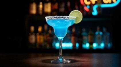 Blue Margarita in a salt-rimmed margarita glass, electric blue colour with lime wheel garnish