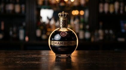 Chambord raspberry liqueur bottle with crown-style stopper on a dark bar.