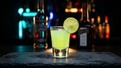 Kamikaze shot in a shooter glass with vodka, triple sec and lime juice, lime wheel garnish