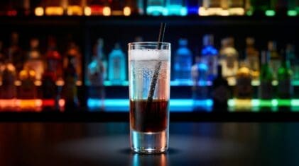 Mind Eraser shot in a tall shot glass with layered Kahlua, vodka and soda water with a straw