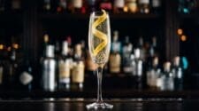 Pale golden French 75 champagne cocktail with a lemon twist spiral