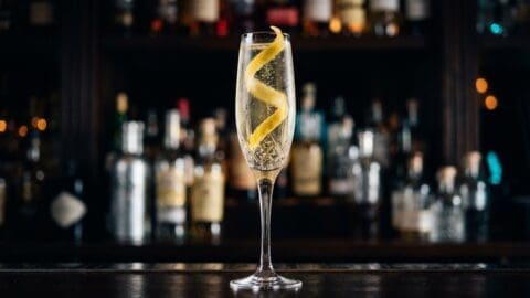 Pale golden French 75 champagne cocktail with a lemon twist spiral