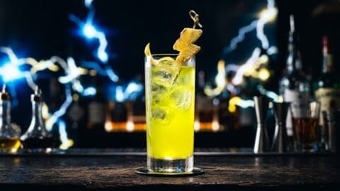 Electric yellow vodka highball with candied ginger lightning bolt garnish